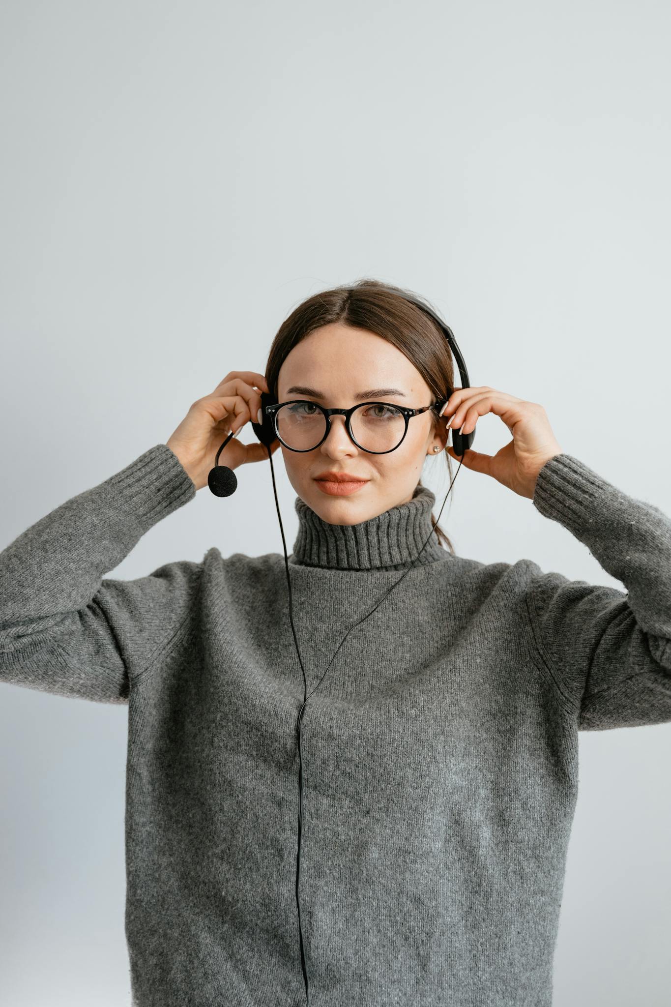 Caucasian woman in gray sweater with headset offering customer service assistance.